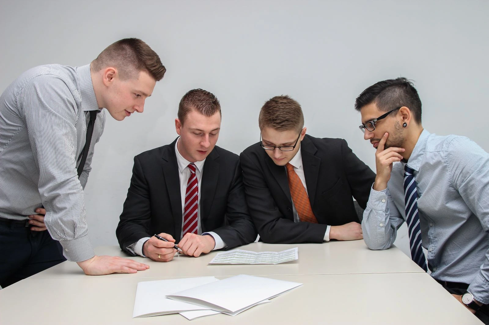 Four men looking at the paper on the desk discussing about career development.