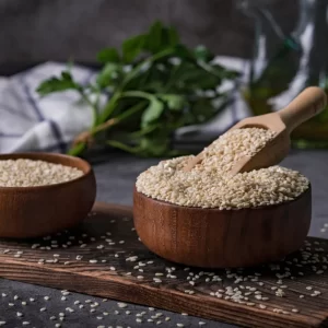 white sesame seeds in a wooden spoon on dark table sesame oil in jar and seeds concept sesame