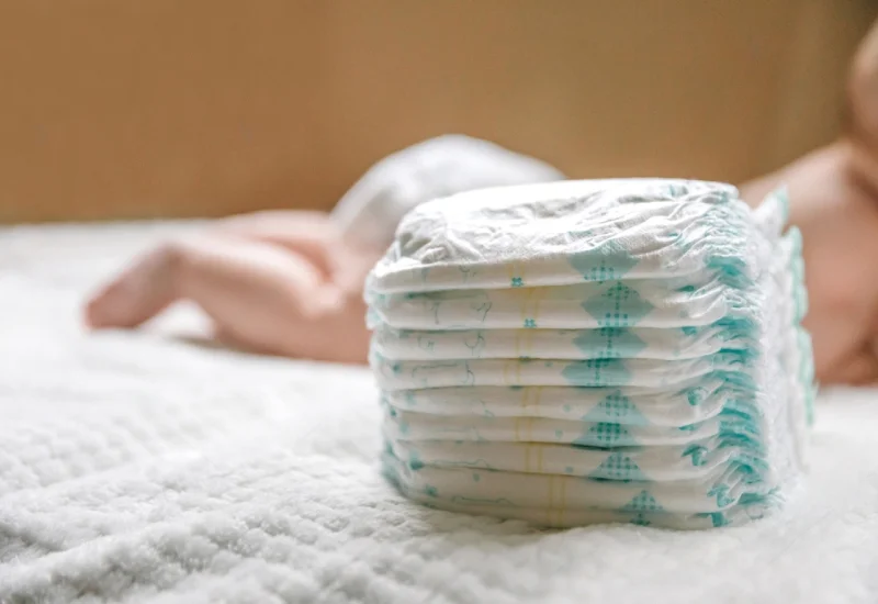 a baby in a diaper at the age of two months and a stack of diapers how to choose baby diapers